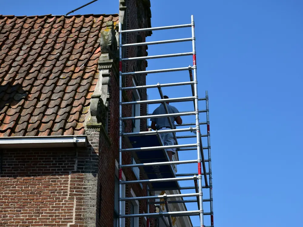 Échafaudage dressé le long d'une façade, au niveau d'une toiture en tuiles