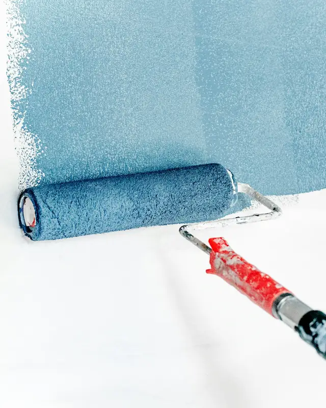 Rouleau appliquant une peinture bleue sur un mur blanc