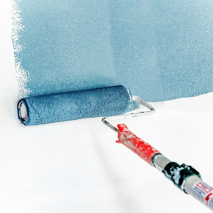 Rouleau appliquant une peinture bleue sur un mur intérieur